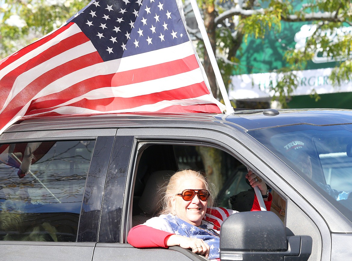 Cindy Abbott smiles as she holds an American flag during Saturday's vehicle parade on Sherman Avenue to support President Donald Trump.