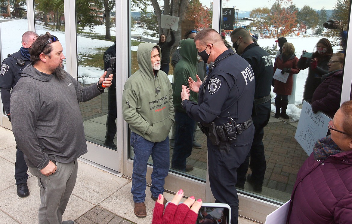 Coeur d'Alene Police Capt. Dave Hagar talks to a man outside the meeting of the Coeur d'Alene City Council Monday, while others in the protest record the incident.