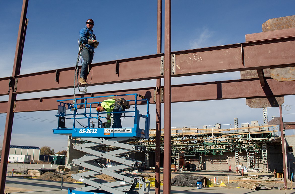 A pair of construction site workers wait on steel beams to be sent over as construction continues at the Vicki Groff Elementary School site in Moses Lake on Tuesday.