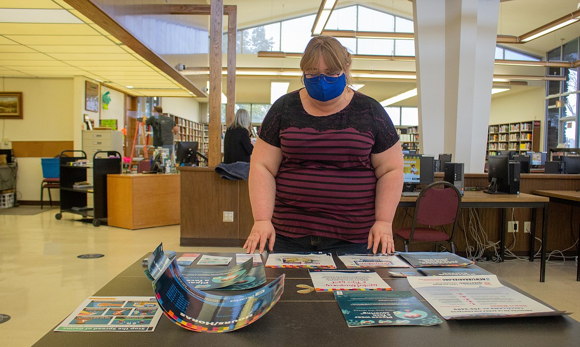 Connie Baulne, Branch Supervisor with Moses Lake Public Library, stands behind a table filled with posters and papers listing new rules and regulations set to go up inside the building before the library reopens to patrons on Monday.