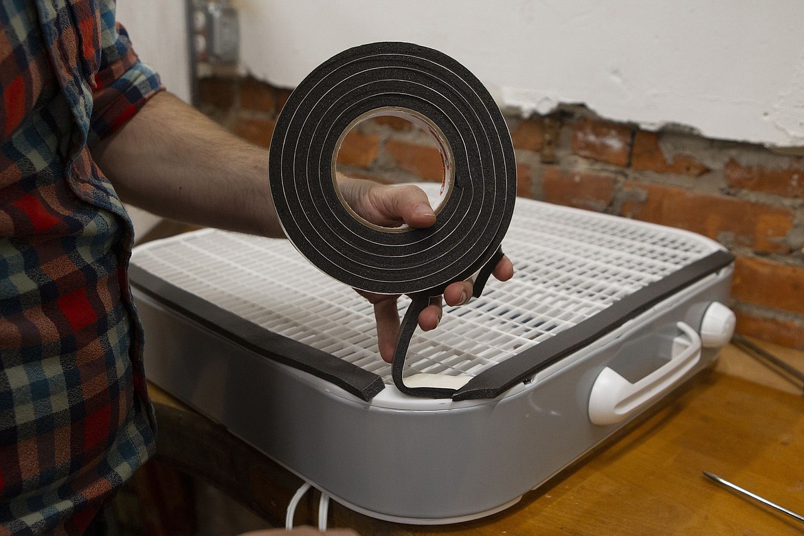 Adhesive insulation is put to box fan to create a seal. Tom Meyer, President of Hive76, and Inquirer writer Tom Avril demonstrate how to build an air filtering system out of a box fan and some furnace filters on Oct. 14, 2020