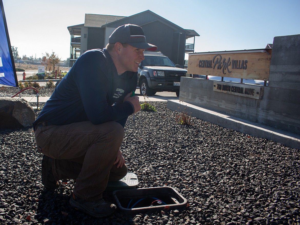 Matt Ahmann, owner and operator of Masterpiece Landscape in Moses Lake, keeps an eye on sprinklers as he blows out a system at Central Park Villas apartments on Thursday.