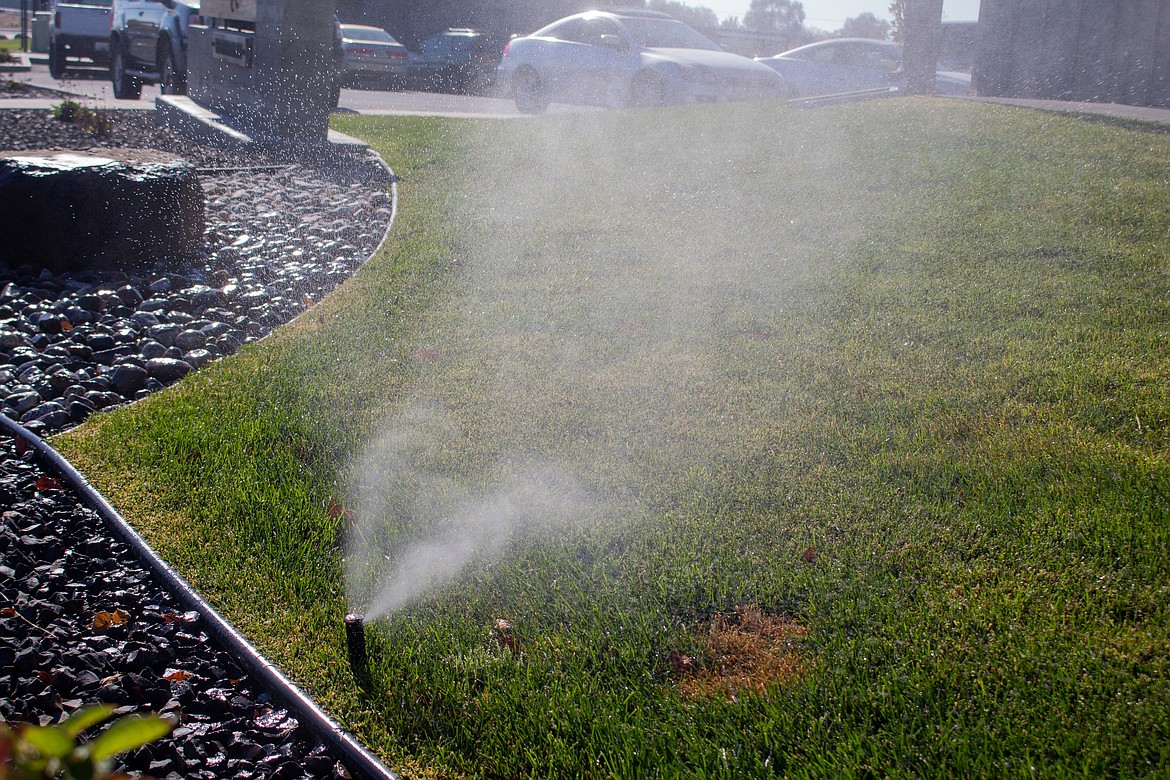 Water sprays out of a sprinkler head at Central Park Villas in Moses Lake as Matt Ahmann, with Masterpiece Landscaping, gets the system ready to be shut down for winter.
