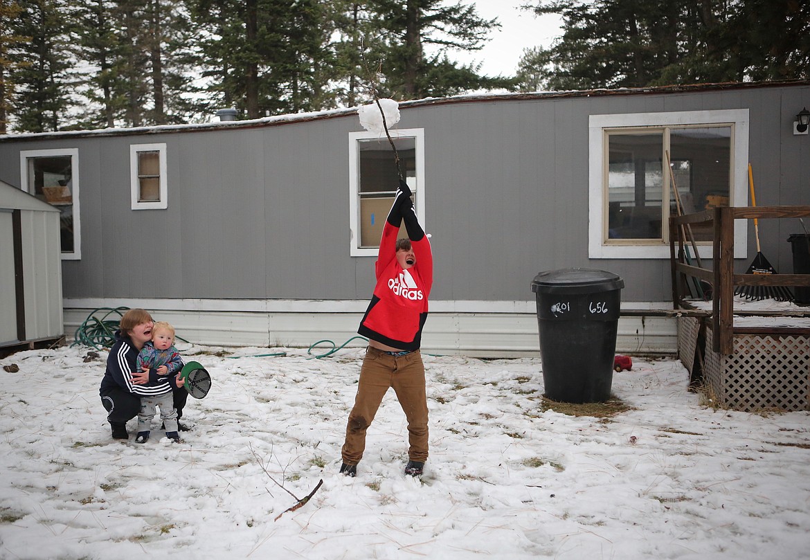 Tyrell Small, 10, takes a swing at a snowball while playing outside the mobile home that they will live in once repairs are finished. 
Mackenzie Reiss/Daily Inter Lake