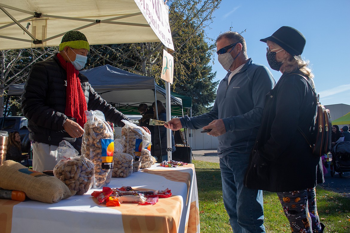 Weng-Cheong Lim serves a pair of patrons at the Roasted Peanut Company stand on Saturday morning at the Moses Lake Farmers Market.