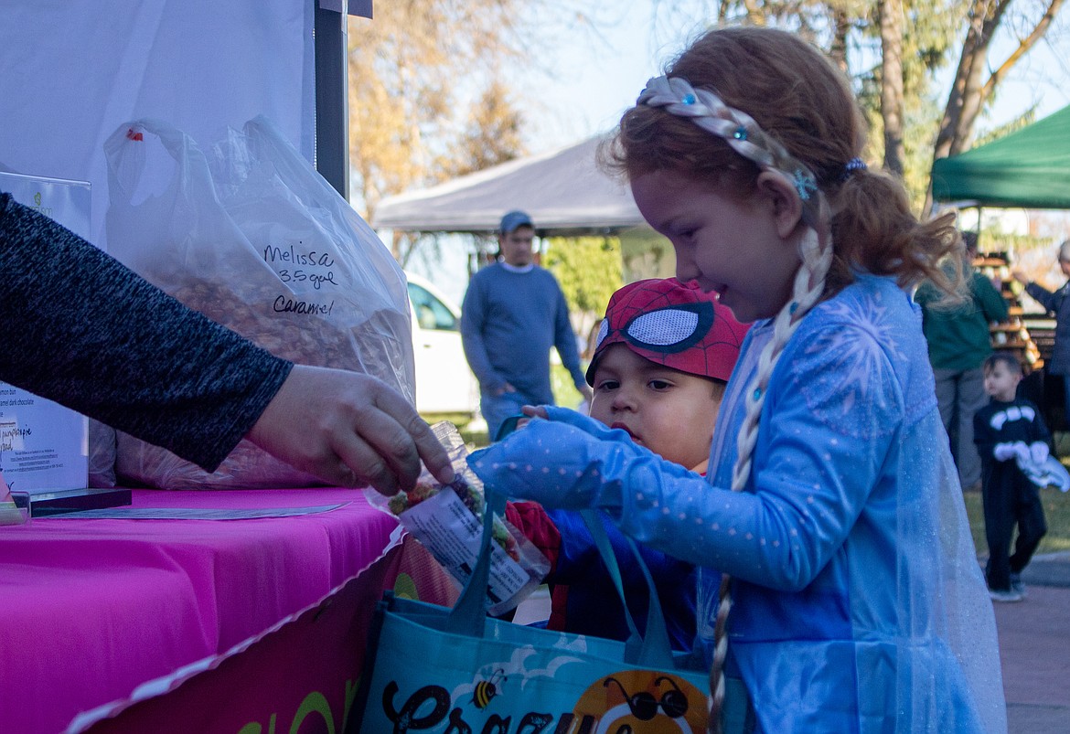 A pair of trick-or-treaters excitedly accept candy from Debbie Doran-Martinez at the Moses Lake Farmers Market on Saturday.