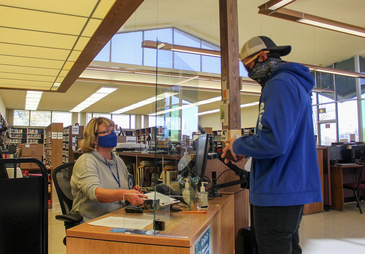 Kim Thomas, customer technician at Moses Lake Public Library, helps Steven Otto sign up for his library card on Monday as the library reopens to the public.