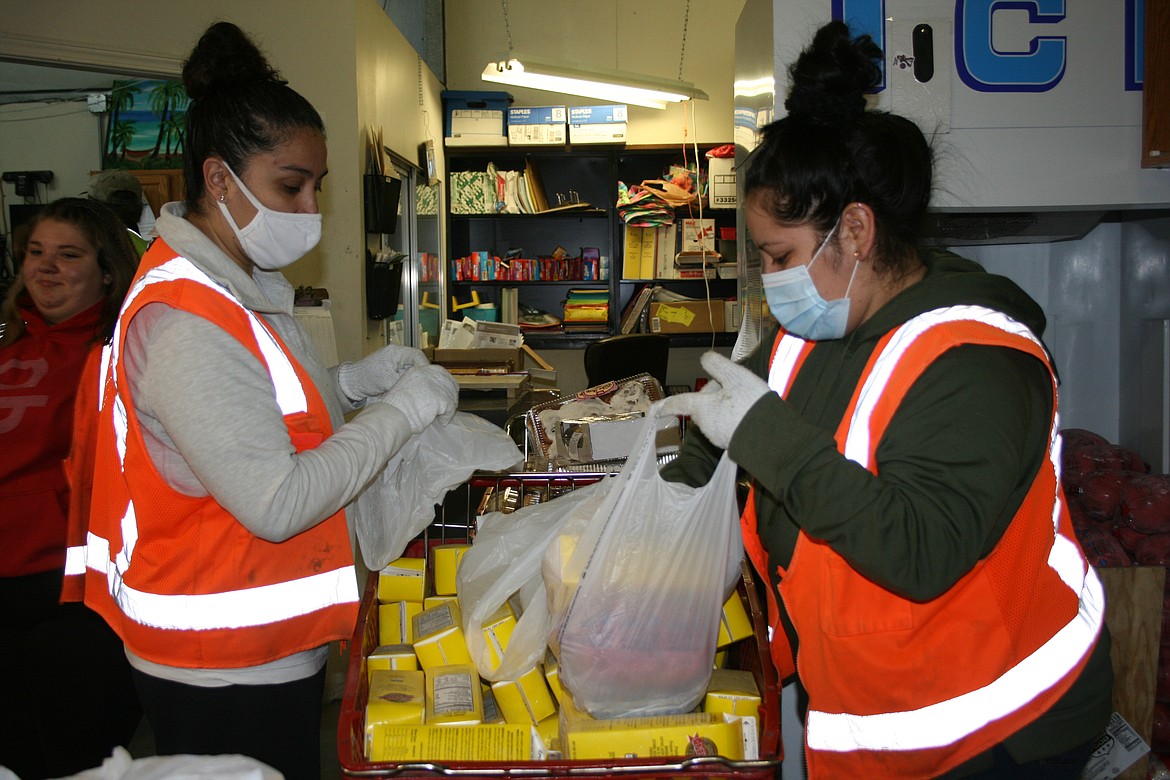 Alicia Murguia (left) and Adeldia Sanchez (right) stuff bags for distribution at the Moses Lake Food Bank. Food banks throughout the region are looking for donations of food and money as the 2020 holiday season approaches.