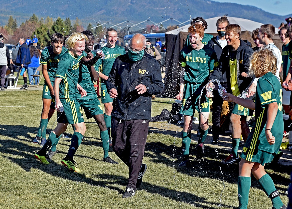 The Whitefish boys soccer team celebrates its third-straight state title by thowing water on head coach John Lacey following the final whistle. (Whitney England/Whitefish Pilot)