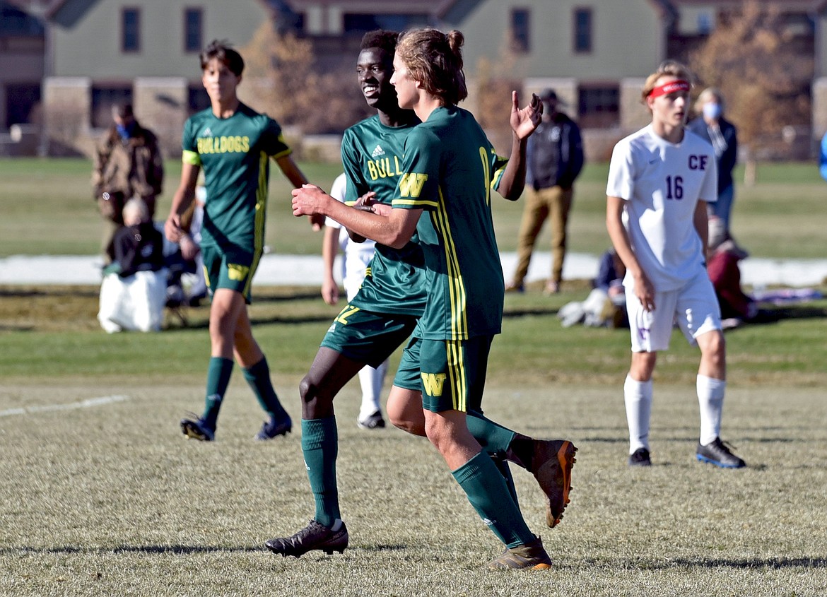 Bulldog Marvin Kimera (22) congratulates his teammate Gabe Menicke after a goal in the Class A state final Saturday at Smith Fields. (Whitney England/Whitefish Pilot)