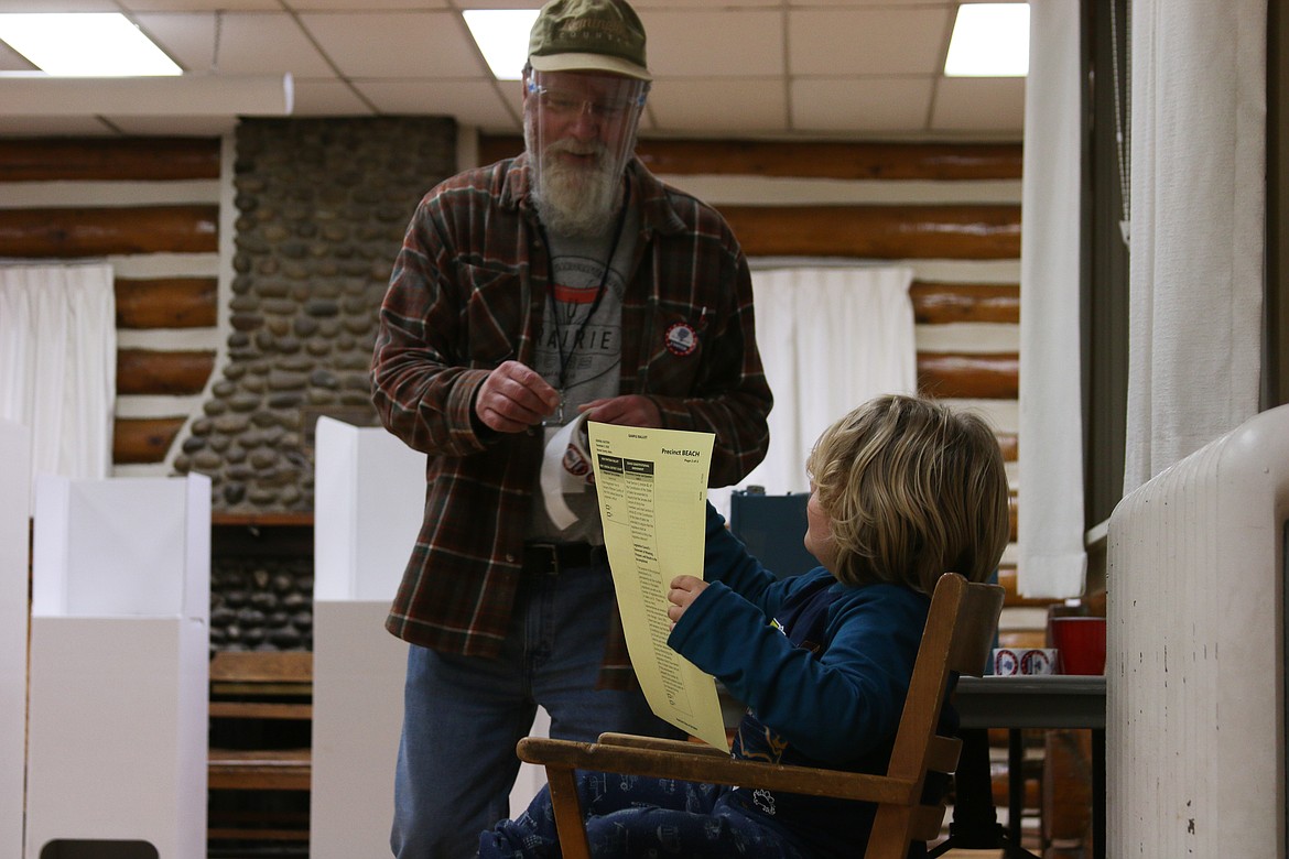 Rob Manly, one of the poll workers at the Sandpoint Community Hall, talks to a young Sandpoint resident, who looks at a sample ballot while their parents vote.