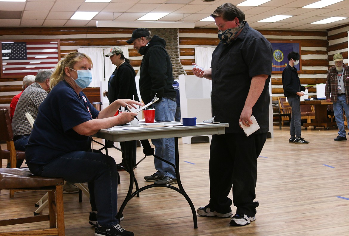 Poll worker Susan Olson helps a young man vote at the Sandpoint Community Hall Tuesday night.