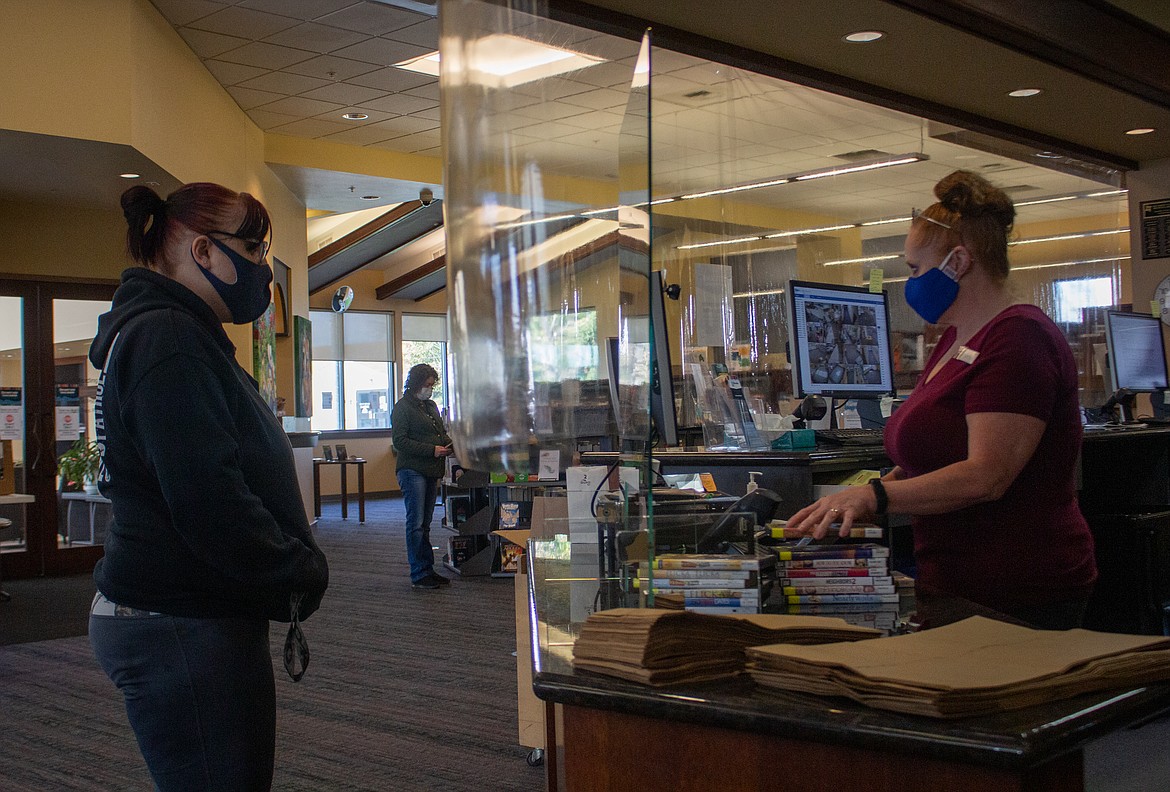 Marissa Postlethwaite, left, stopped by to check out a couple of stacks of movies from the Quincy Public Library on Wednesday as Dottie Van Baugh, right, helps her get everything checked out.