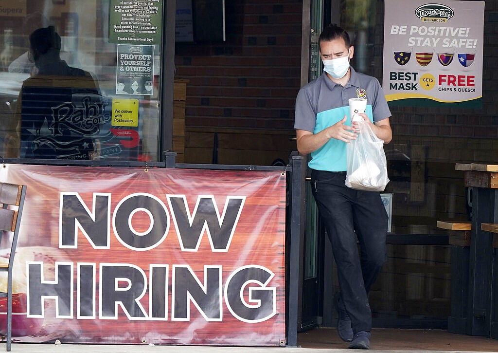 In this Sept. 2, 2020 file photo, a customer wears a face mask as they carry their order past a now hiring sign at an eatery in Richardson, Texas. On Thursday, Nov. 5, the number of Americans seeking unemployment benefits fell slightly last week to 751,000, a still-historically high level that shows that many employers keep cutting jobs in the face of the accelerating pandemic.