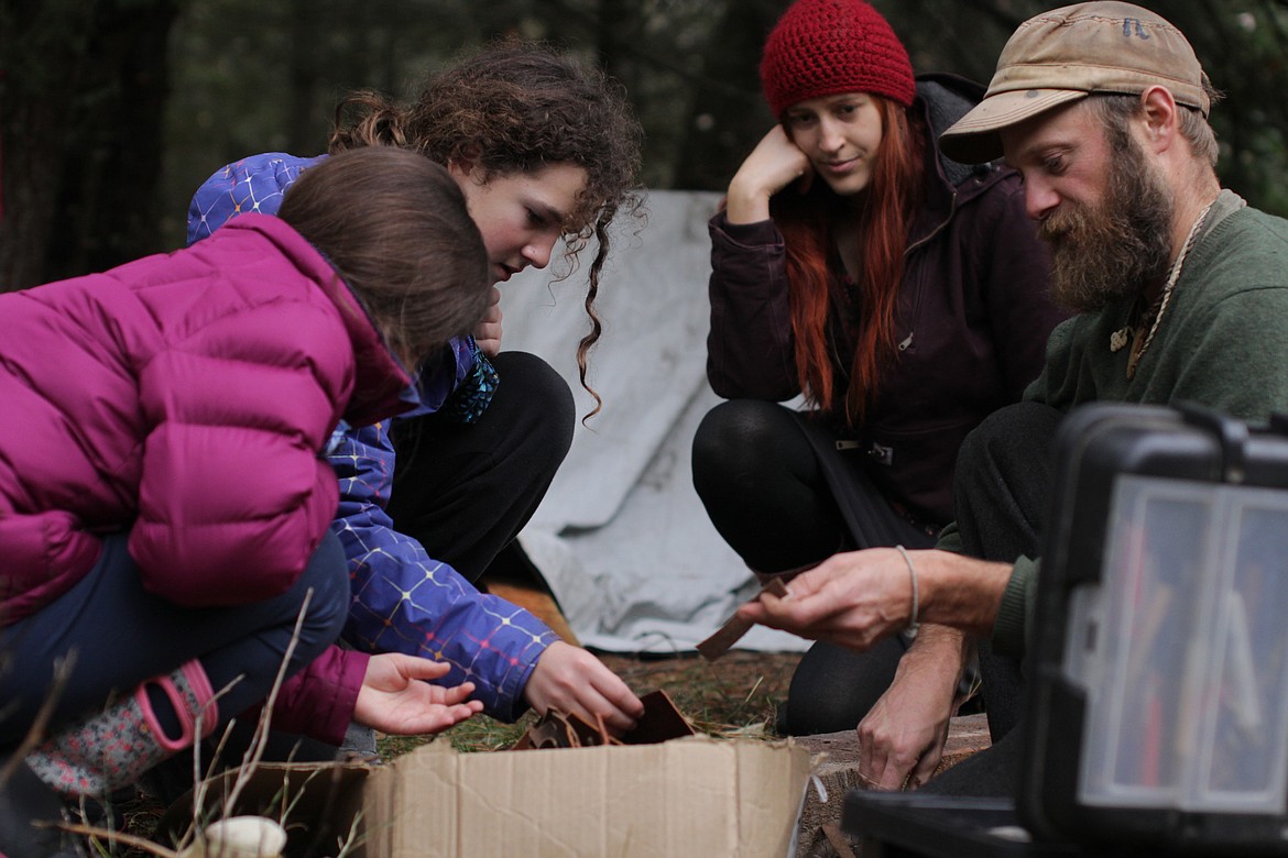 Dave Kretzschmar shows fifth graders Madison Jordan and Fiona Smith how to tool leather Wednesday afternoon at Pine Street Woods.