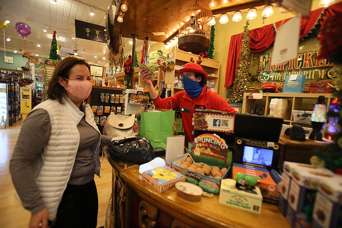 Figpickels Toy Emporium customer Sandy Winant of Coeur d'Alene laughs as employee Austin Sommer makes a goofy face while handing her change. North Idaho retailers are going all out with customer service, one-of-a-kind products, creative delivery methods and seasonal deals to court consumers to shop local this holiday season.