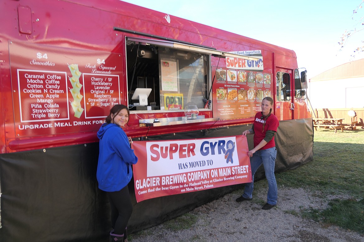 Robin Lopez, right, and a friend set up a sign at Super Gyro's new winter location. "We wanted to make this truck part of the community," Robin said. (Carolyn Hidy/Lake County Leader)