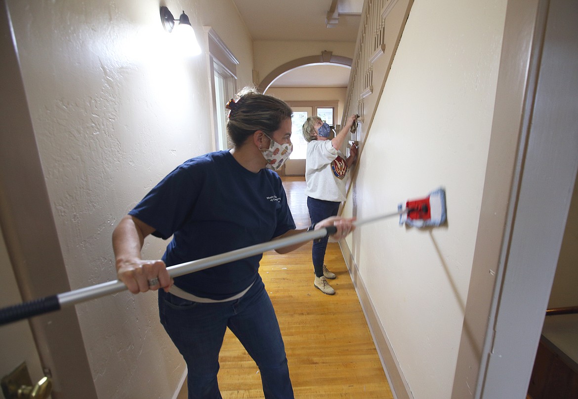 Monica Thulon, left, and Deborah Mitchell wipe down a wall at the Hamilton House, which is the new home of the Music Conservatory of Coeur d'Alene, on Saturday.