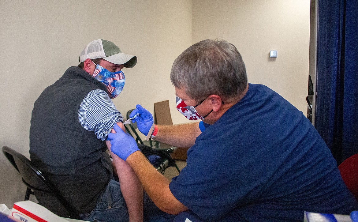 Left, Milton Miller, holds out his arm as volunteer Lloyd Steven administers the flu vaccine at the Free Flu Shot Clinic at Samaritan Clinic on Patton in Moses Lake.