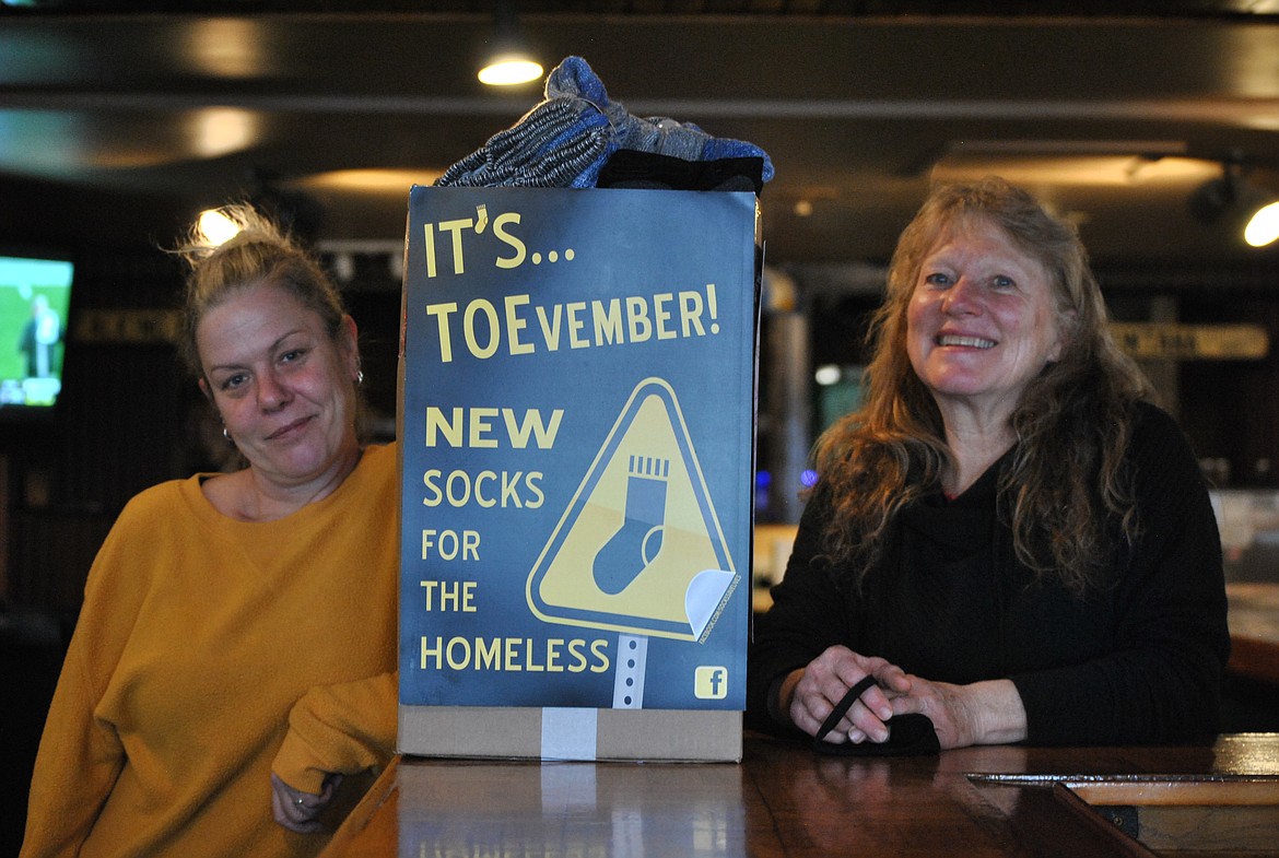 Karen Bondurant and bartender Debby Norris proudly show off their over flowing box of new socks for the charitable organization called TOEvember. This is the fourth year the Talking Bird in St. Regis has participated and they are hoping next year to get a drop box at one of the bars in Superior to have some friendly competition. (Amy Quinlivan/Mineral Independent)