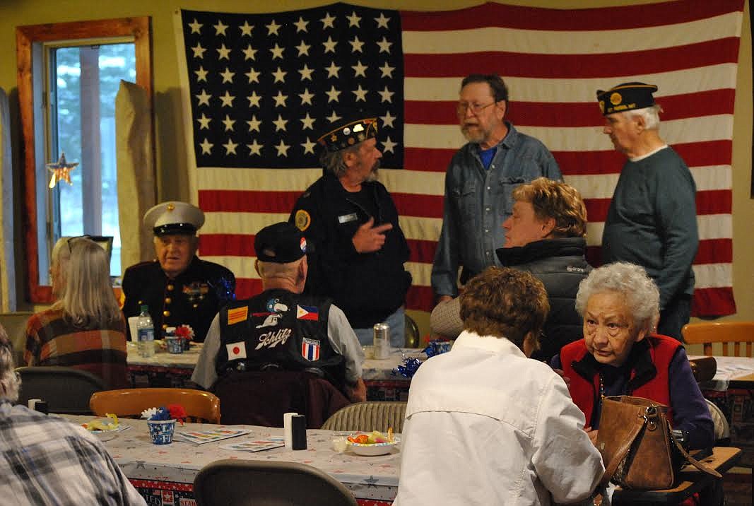 COVID-19 may have parred down Veterans Day events in Mineral County, but members from the Ray Welch American Legion Post 13 in St. Regis gathered to observe the day and share fellowship for several reasons. Veterans and their families enjoyed a barbecue dinner, and also took the time to honor U.S. Marine John Cochran (white utility cover cap) with a bronze plaque in recognition of his donation of the land that gave the Legion Post a permanent home. The 48-star flag that hangs on the wall belongs to John Cochran, his mother sent it to him while he was stationed on Yellow Island in 1952. (Amy Quinlivan/Mineral Independent)