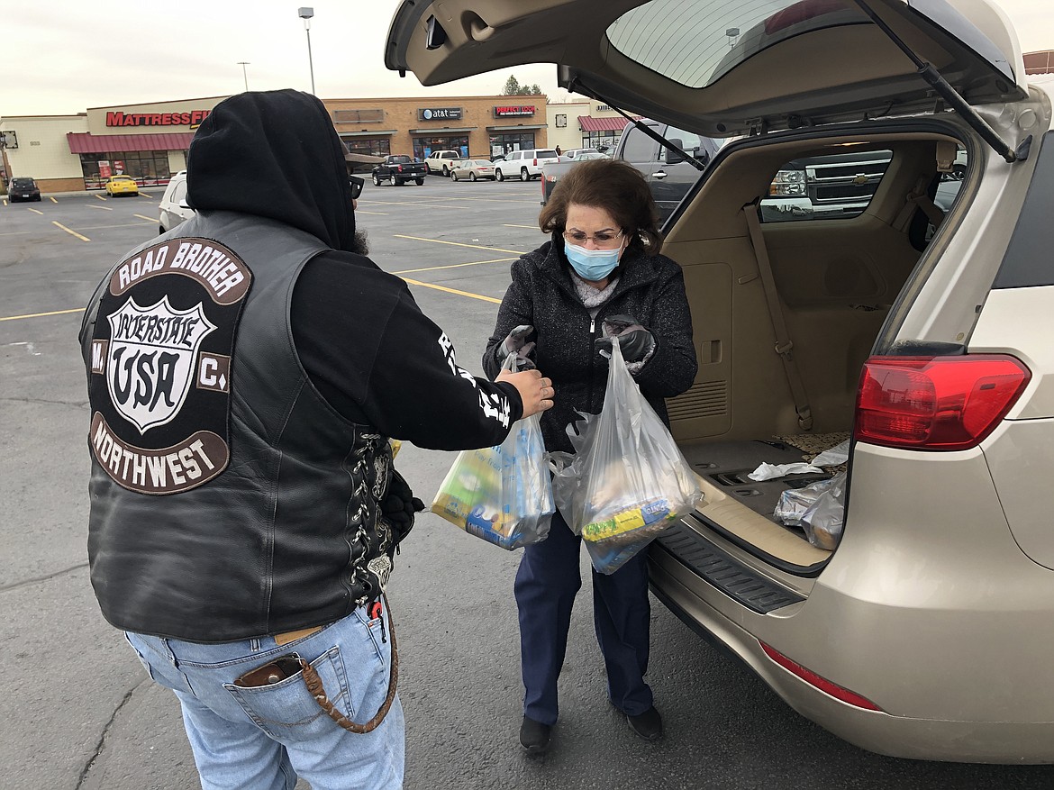 Moses Lake resident Maria Martinez hands two bags of groceries to Road Brother Twinkie during that Road Brothers Motorcycle Club’s annual Thanksgiving and Christmas food drive on Saturday.