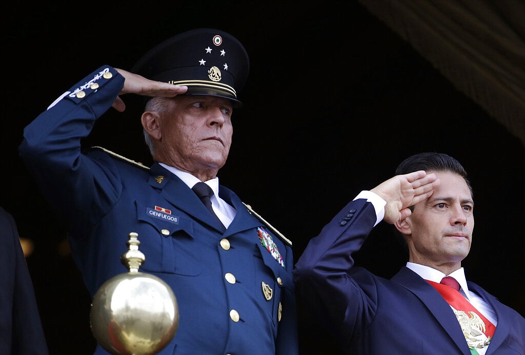 In this Sept. 16, 2016 file photo, Defense Secretary Gen. Salvador Cienfuegos, left, and Mexico's President Enrique Pena Nieto, salute during the annual Independence Day military parade in Mexico City's main square. U.S. prosecutors on Wednesday, Nov. 18, 2020, formally dropped a drug trafficking and money laundering case against Gen. Cienfuegos, a decision that came after Mexico threatened to cut off cooperation with U.S. authorities unless the general was sent home.