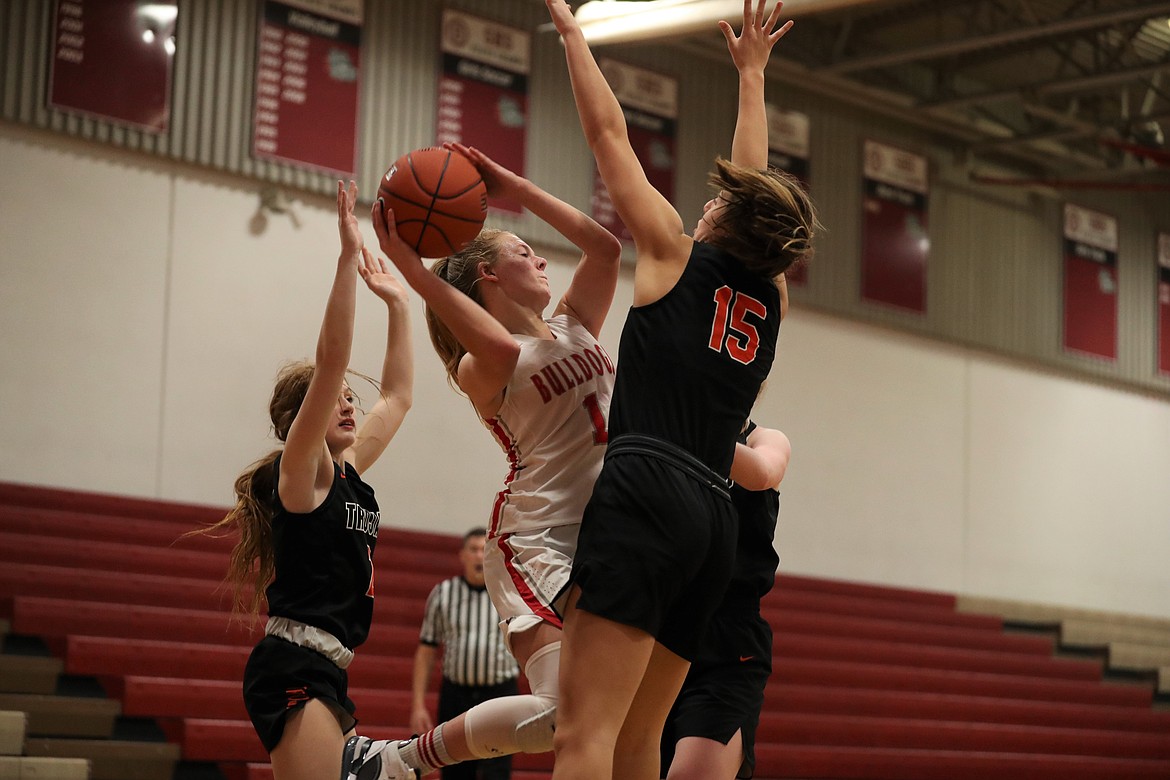 Sophomore Kelsey Cessna attempts to thread a pass through a trio of Trojan defenders.