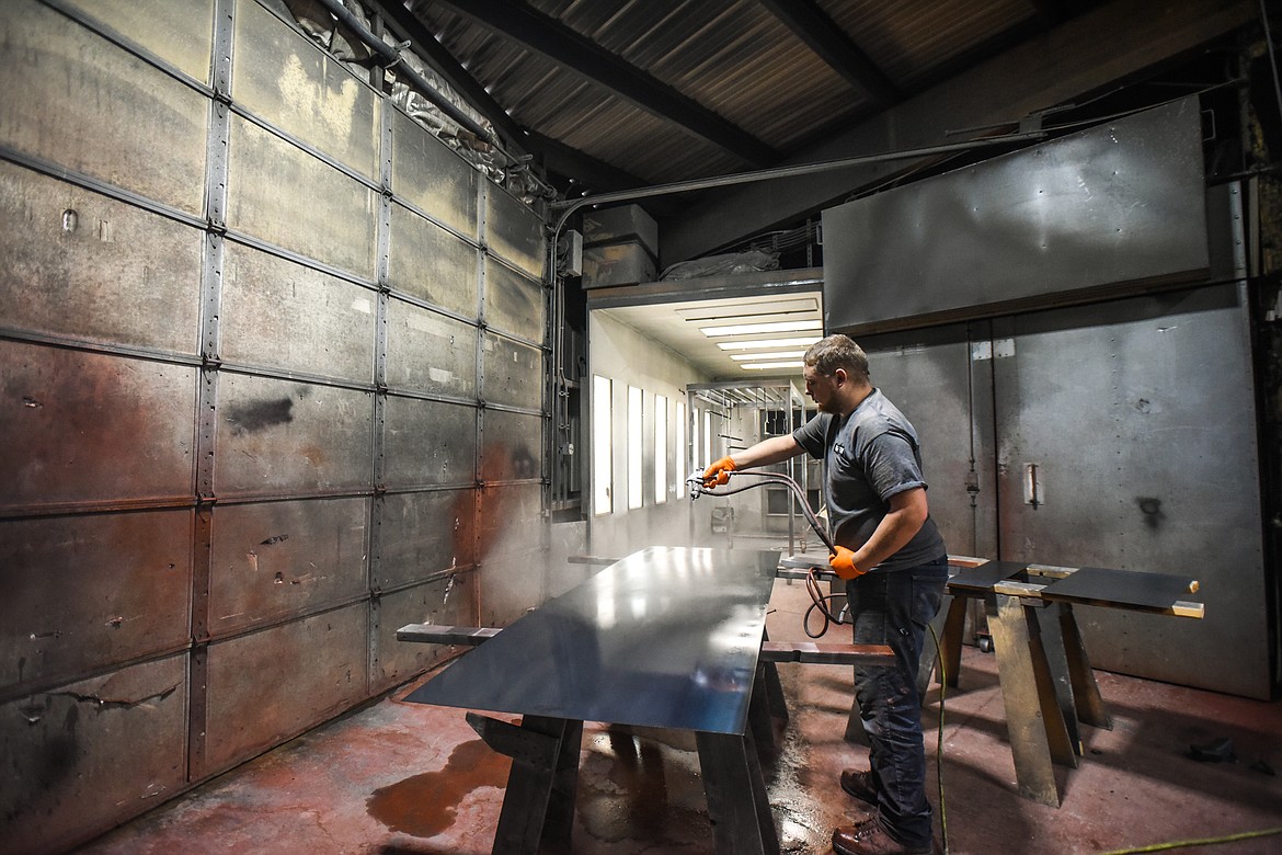 A worker applies clear coat to pieces of mild steel at Acutech Metalworks on Wednesday, Nov. 18. (Casey Kreider/Daily Inter Lake)