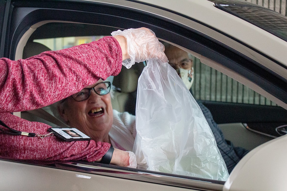 A pair of smiles light up inside the car as Jennifer Killian hands the two community members their free Thanksgiving dinners at the Community Thanksgiving Dinner-to-go event at the Elks Lodge in Moses Lake on Wednesday.