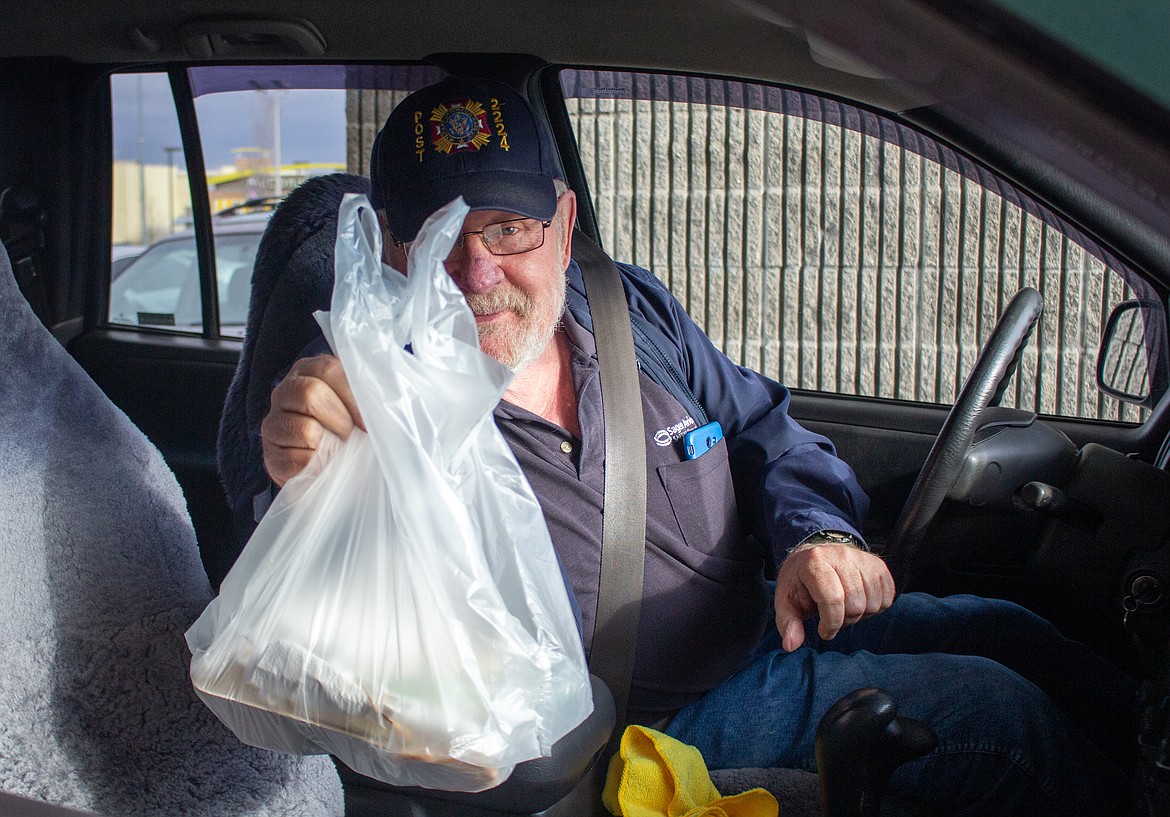 Doug Gambriel holds up his Thanksgiving dinner with a smile after coming through the drive-thru at the Community Thanksgiving Dinner-To-Go at the Elks Lodge in Moses Lake on Wednesday.