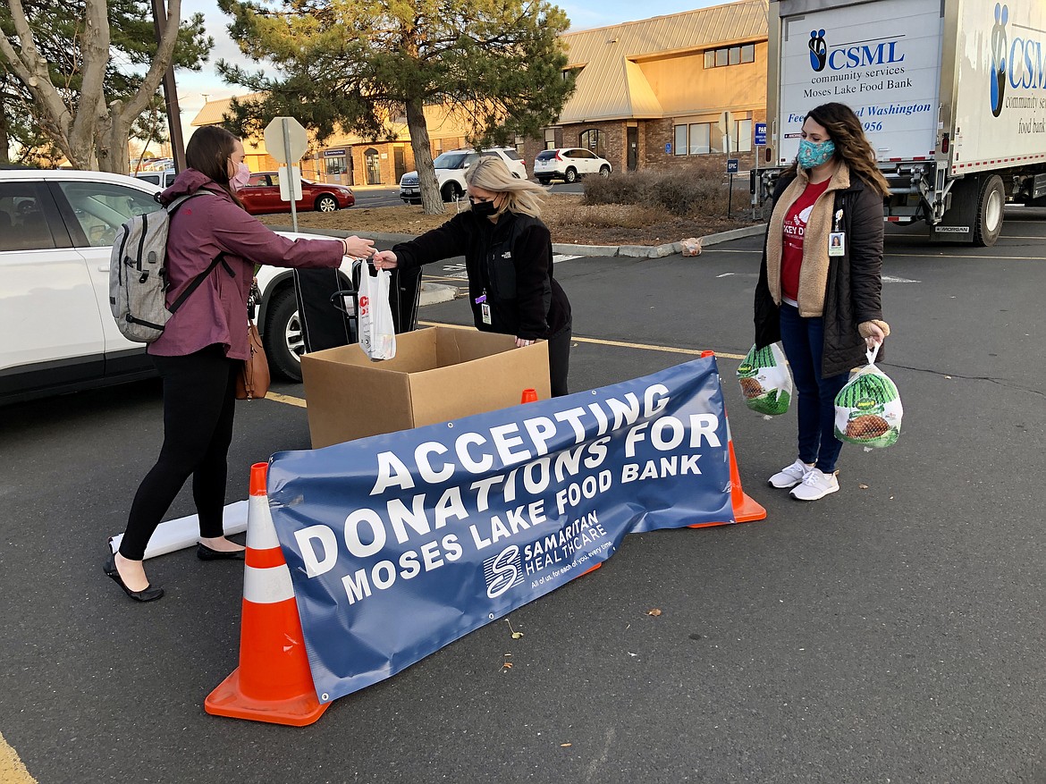 Katie Lewis (right) hands Samaritan Hospital Marketing Coordinator Misty Aguilar a bag of food Thursday afternoon as part of Samaritan's two-day food drive for the Moses Lake Food Bank, which continues through today. According to Samaritan Volunteer Coordinator Rachelle Lange (holding the turkeys), Samaritan is accepting frozen turkeys, any non-perishable foods, or cash, and food will distributed next week to needy families across the area.