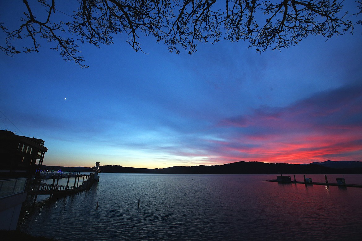 The setting sun casts a glow over the mountains and on the  Lake Coeur d'Alene while the moon rises Friday evening.