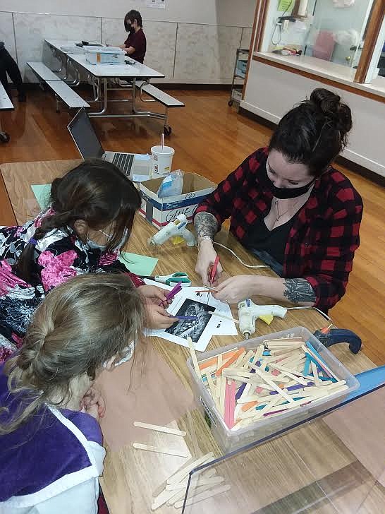 Alberton teacher Ashley Reel uses a hot glue gun to demonstrate the basics of building a log cabin. (Monte Turner/Mineral Independent)