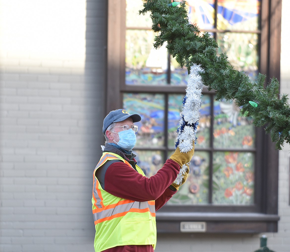 Volunteers hang the winter decorations downtown Sunday morning. (Heidi Desch/Whitefish Pilot)