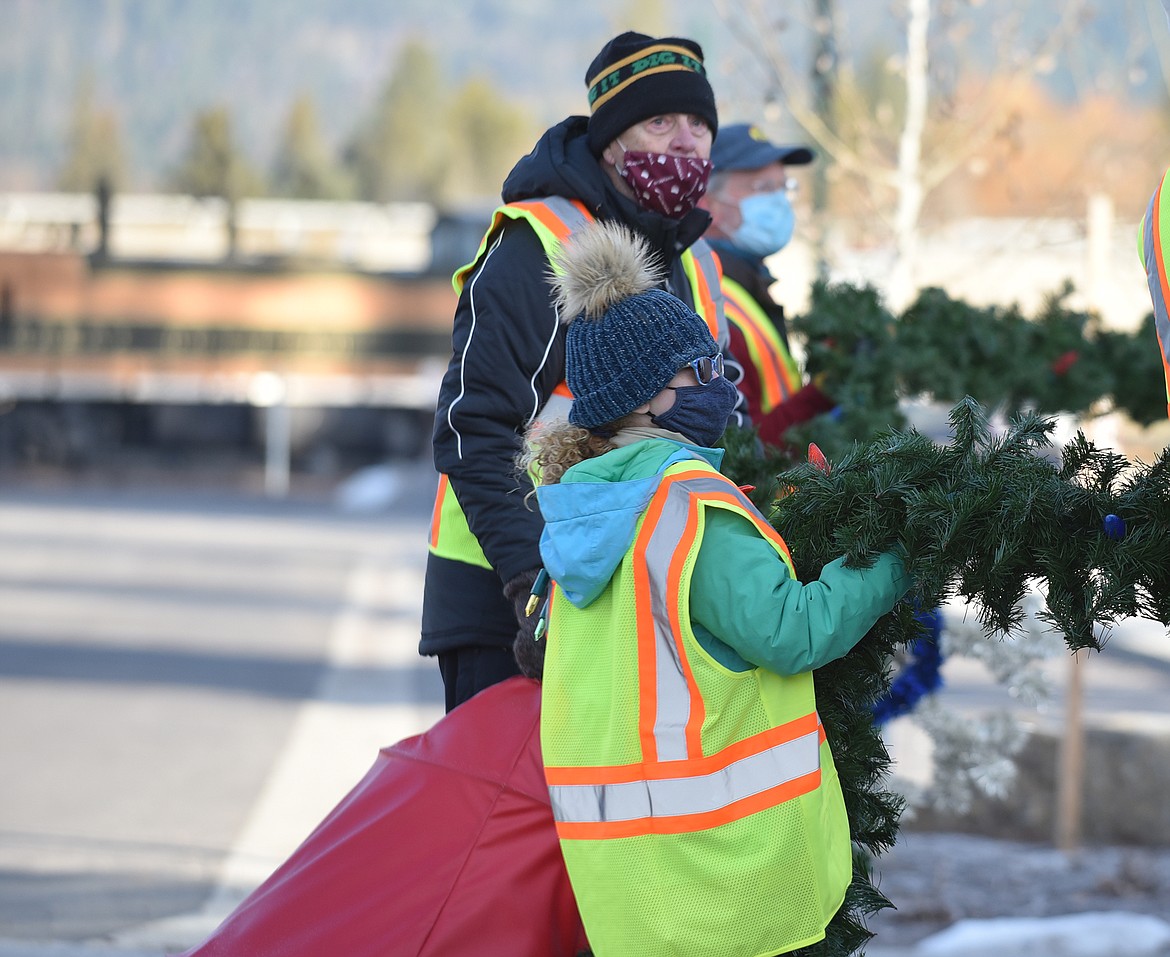 Volunteers hang the winter decorations downtown Sunday morning. (Heidi Desch/Whitefish Pilot)