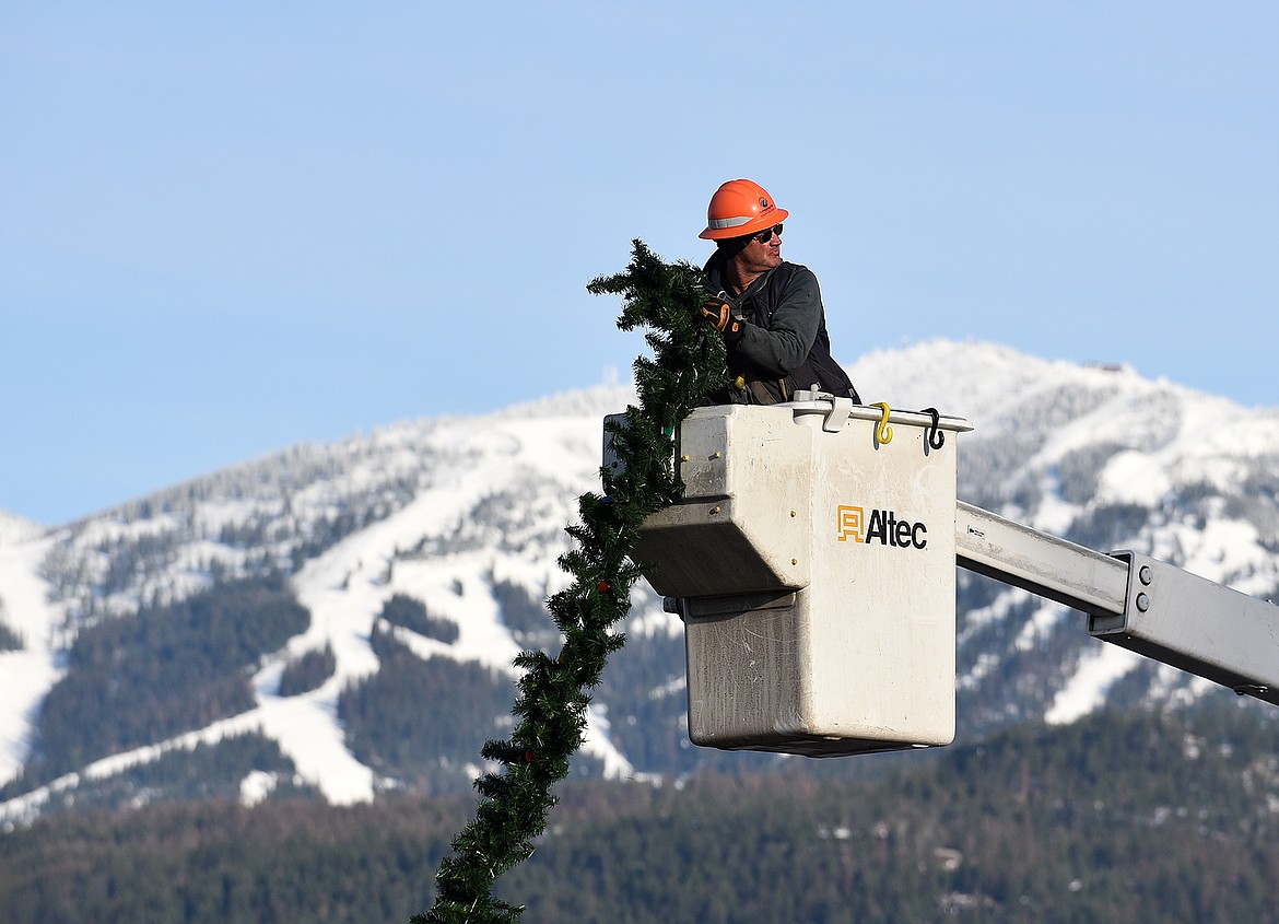 Volunteers hang the winter decorations downtown Sunday morning. (Heidi Desch/Whitefish Pilot)