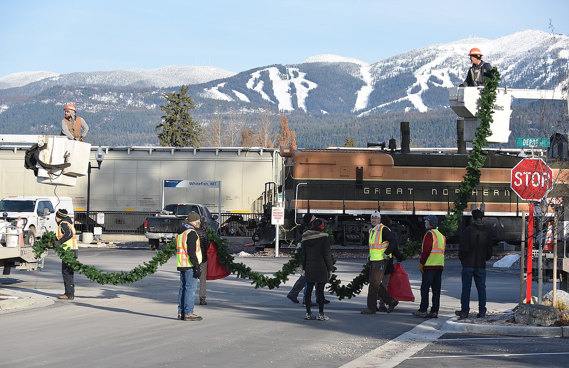 Volunteers hang the winter decorations downtown Sunday morning. (Heidi Desch/Whitefish Pilot)