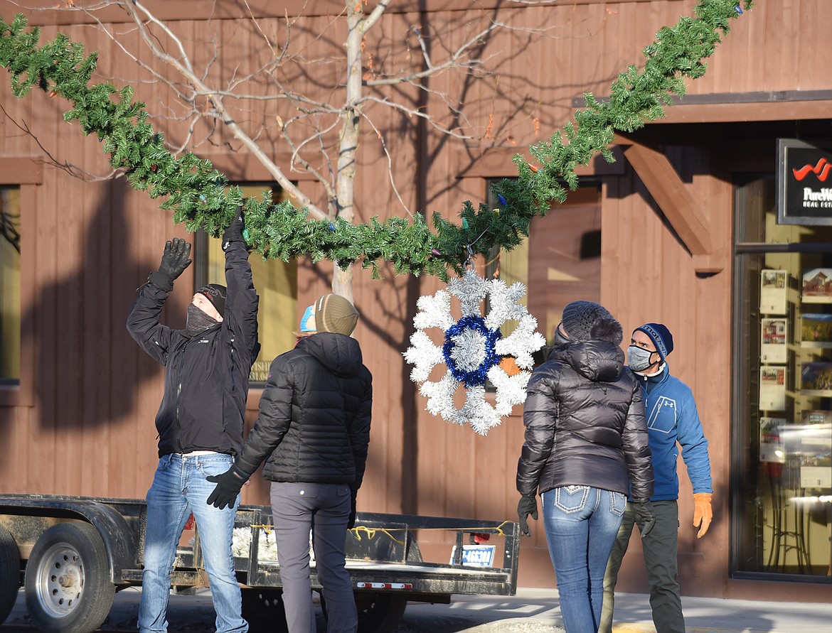 Volunteers hang the winter decorations downtown Sunday morning. (Heidi Desch/Whitefish Pilot)