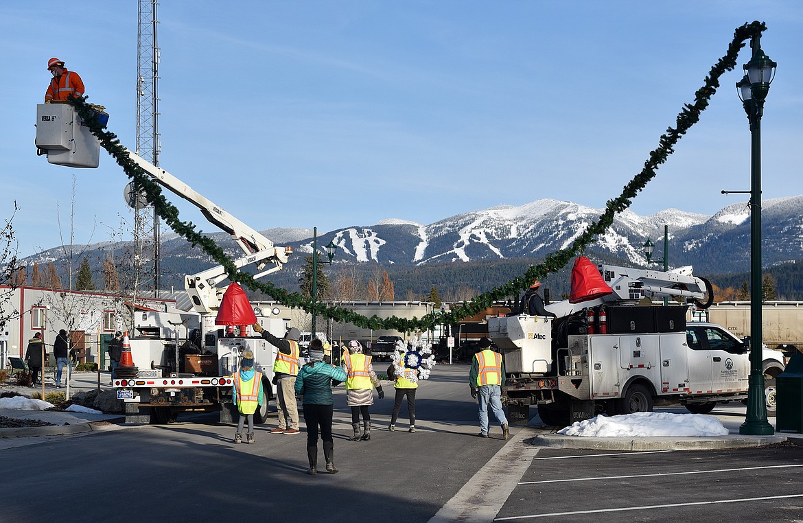 Volunteers hang the winter decorations downtown Sunday morning. (Heidi Desch/Whitefish Pilot)