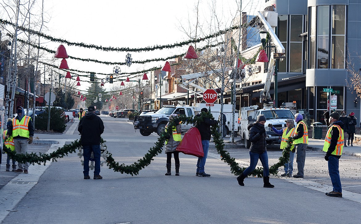 Volunteers hang the winter decorations downtown Sunday morning. (Heidi Desch/Whitefish Pilot)