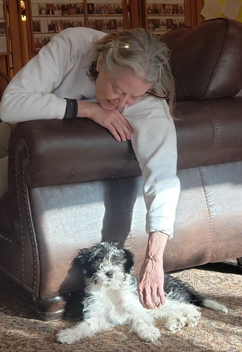 Paulette Ketner leans over the couch to pet Frasier who is on-duty.