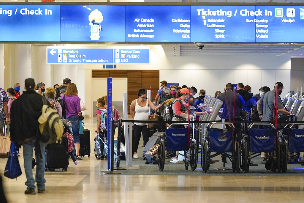 Holiday travelers check in at kiosks near an airline counter at Orlando International Airport Tuesday, Nov. 24, 2020, in Orlando, Fla.