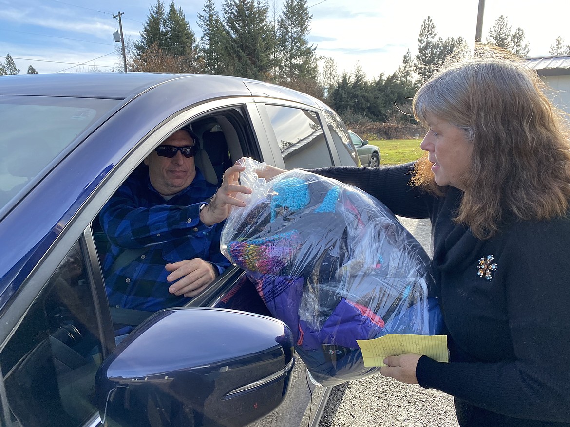 Sue Bartholomew passed a bag of clothing to John Crane at the Knights of Columbus giveaway that will help keep his four children warm and cozy all winter long. (MADISON HARDY/Press)