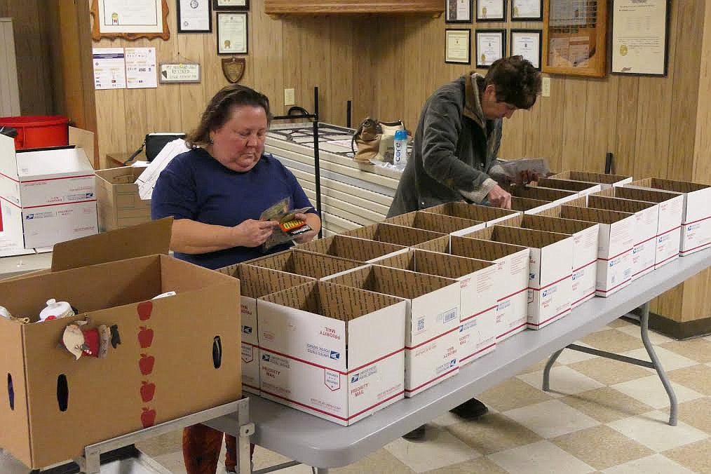 Plains residents and VWF Auxiliary members Deborah Davis (blue shirt) and Cindy Gray, (gray sweater) packing boxes of goodies for those serving away from home. (Chuck Bandel/Valley Press)