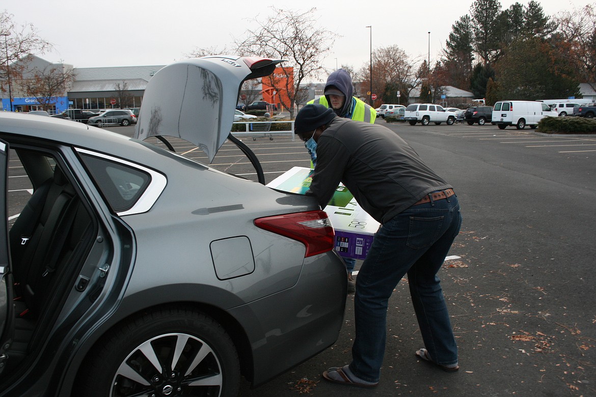 Dave Nwobu (foreground) and Samuel Huntiziner load Nwobu's newly purchased television on Black Friday.