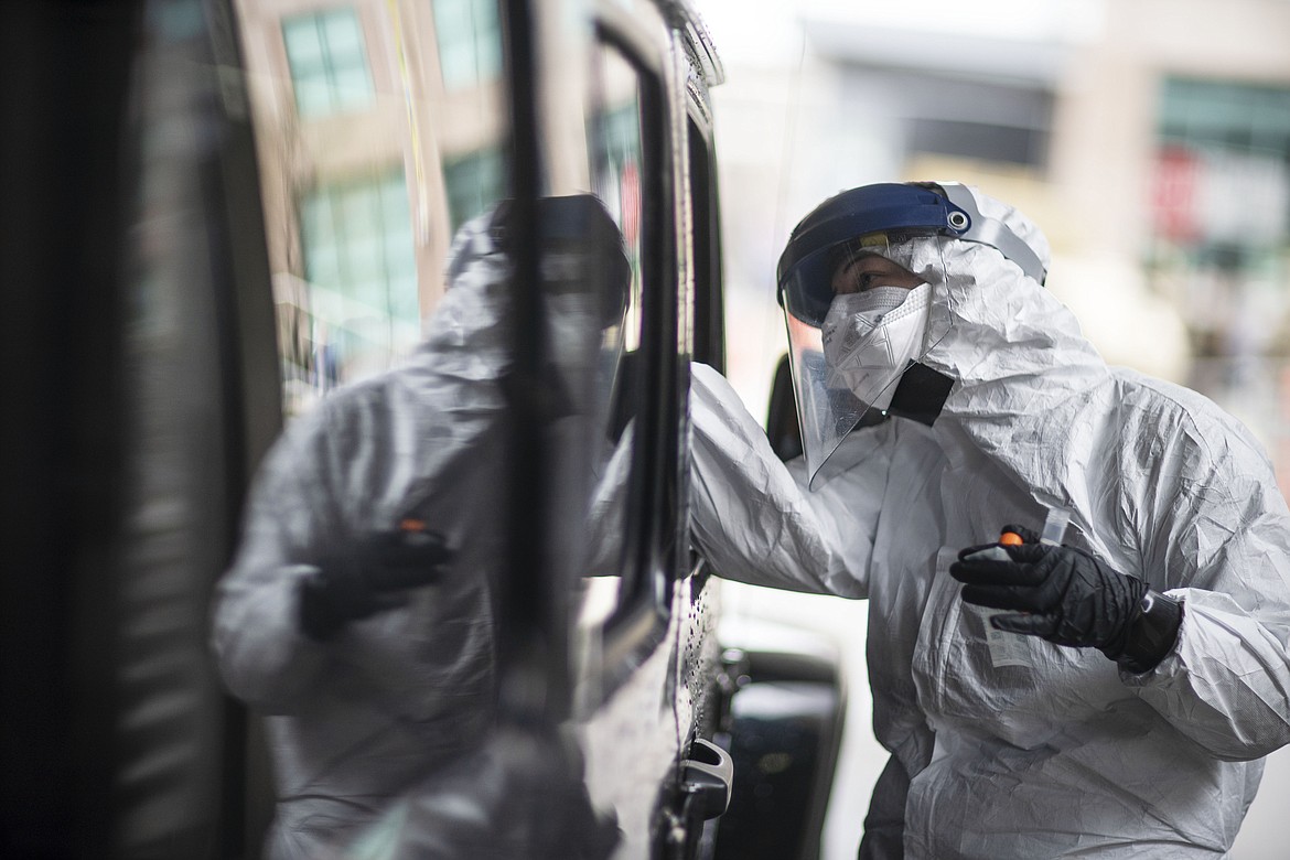 A passenger gets swabbed for COVID-19 at a testing site at the convention center in Providence, R.I, Tuesday, Dec. 1, 2020. Amid the coronavirus resurgence, states have begun reopening field hospitals to handle an influx of sick patients that is pushing health care systems — and their workers — to the breaking point. Hospitals are bringing in mobile morgues. And funerals are once again being livestreamed or performed as drive-by affairs.