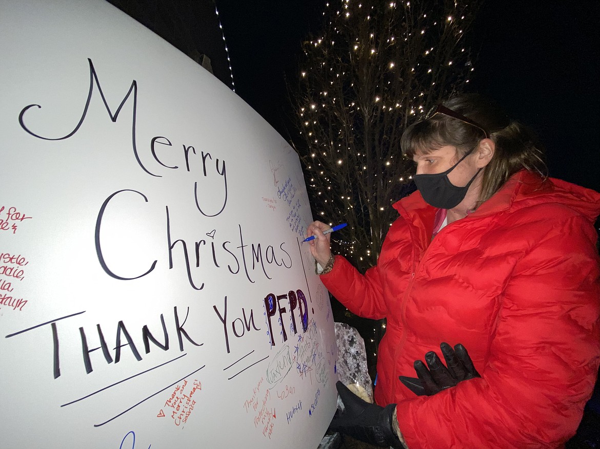 Post Falls resident Joy Grey writes a heartfelt thank you note to the police department Wednesday night at the lighting ceremony hosted by Short Green Landscaping. (MADISON HARDY/Press)