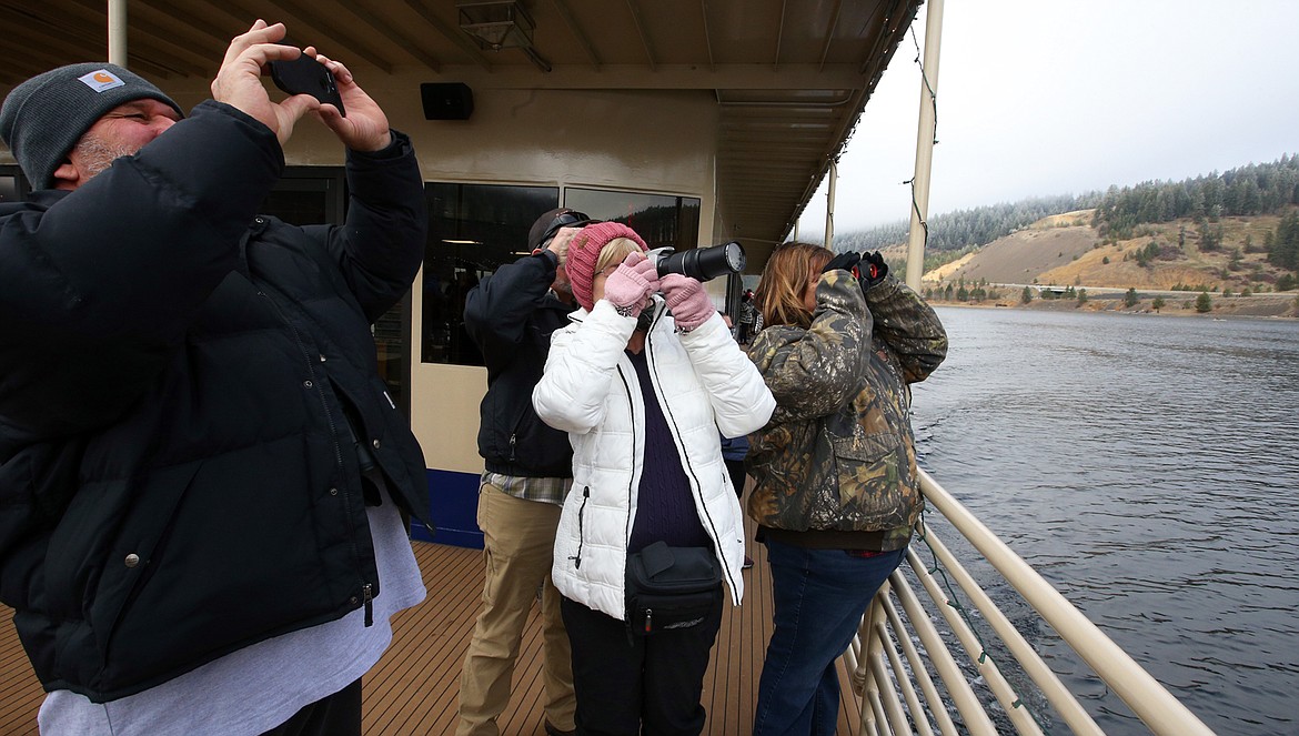 People takes pictures and watch bald eagles from a Lake Coeur d'Alene Cruises boat at Wolf Lodge Bay on Saturday.