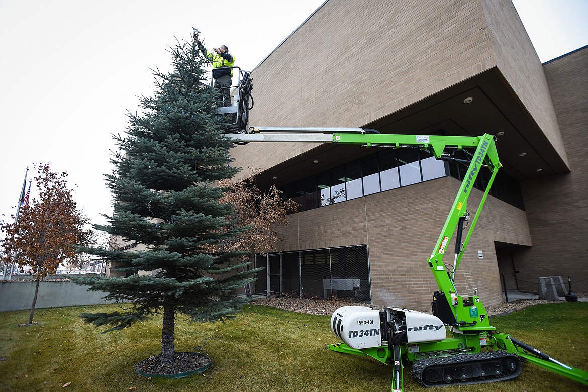 David Covill, building maintenance manager for Flathead County, places a star on top of a tree decorated with blue Christmas lights to commemorate law enforcement officers killed in the line of duty outside the Flathead County Justice Center on Tuesday, Dec. 8. (Casey Kreider/Daily Inter Lake)